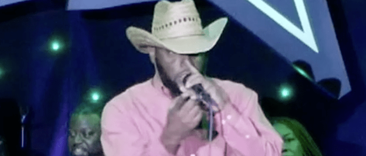 Man in cowboy hat singing on stage.